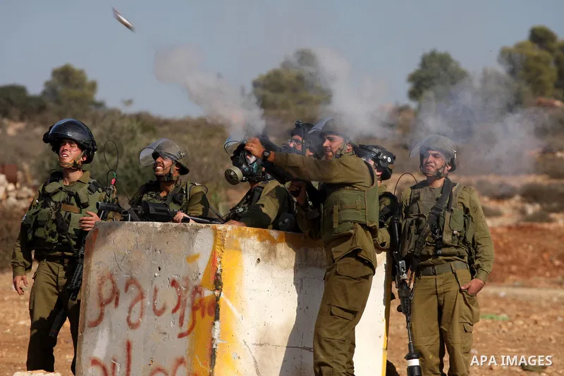 An Israeli soldier fires a tear gas canister towards Palestinian stone throwers during clashes following a weekly demonstration against Israeli settlement expansion, in the West Bank village of Nabi Saleh, on October 28,...