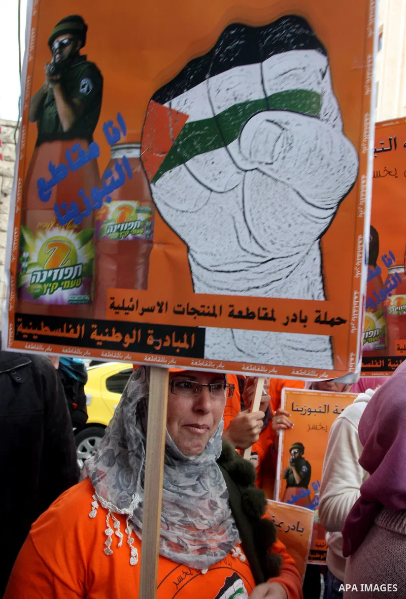 Palestinian demonstrators carry posters and graphics demanding merchants to boycott Israeli settlement products during a protest in the West Bank city of Ramallah October 30,2011. Photo by Issam Rimawi