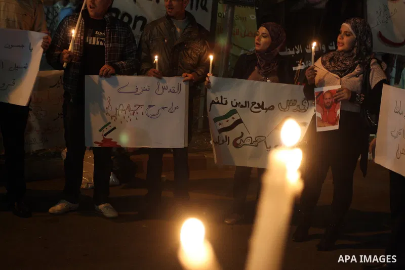 Palestinians hold candles and the Syrian national flag against the Syrian regime and Syrian President Bashar al-Assad in the West Bank city of Ramallah on Oct. 30, 2011. Photo by Issam Rimawi