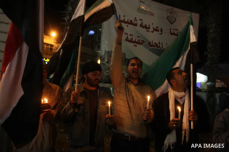 Palestinians hold candles and the Syrian national flag against the Syrian regime and Syrian President Bashar al-Assad in the West Bank city of Ramallah on Oct. 30, 2011. Photo by Issam Rimawi