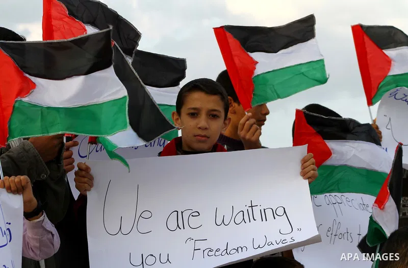 Palestinian children wave national flags during a rally to show their support for a two boat flotilla attempt to reach the Gaza Strip, in the port of Gaza City Friday, Nov. 4, 2011. Israel's military says the navy has bo...
