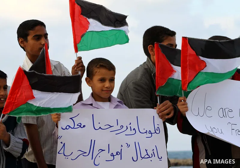 Palestinian children wave national flags during a rally to show their support for a two boat flotilla attempt to reach the Gaza Strip, in the port of Gaza City Friday, Nov. 4, 2011. Israel's military says the navy has bo...