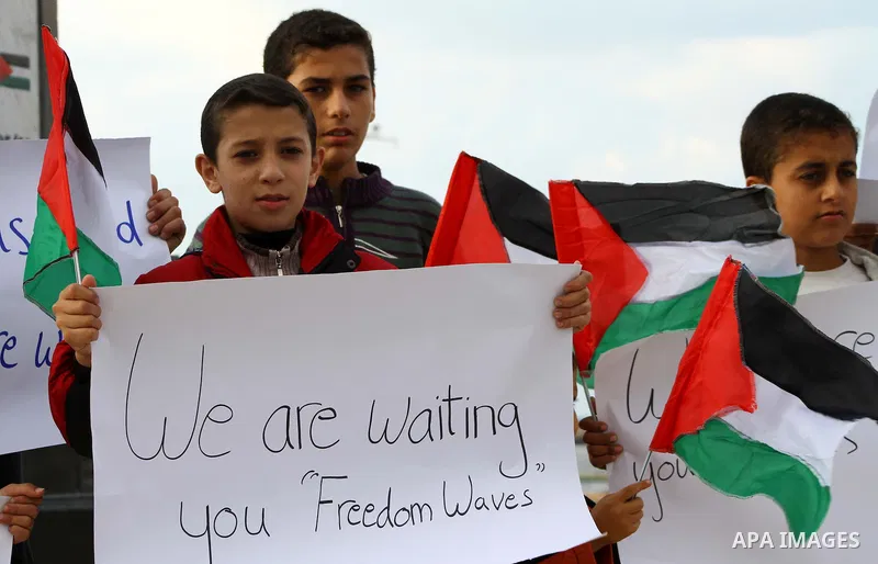 Palestinian children wave national flags during a rally to show their support for a two boat flotilla attempt to reach the Gaza Strip, in the port of Gaza City Friday, Nov. 4, 2011. Israel's military says the navy has bo...
