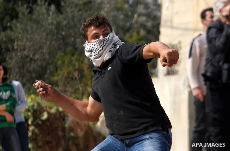 Palestinian youths hurl stones towards Israeli soldiers during clashes following a protest against the closure of a road during the second Intifada (began late September 2000) by Jewish settlers from the nearby settlemen...