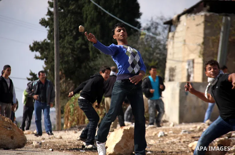 Palestinian youths hurl stones towards Israeli soldiers during clashes following a protest against the closure of a road during the second Intifada (began late September 2000) by Jewish settlers from the nearby settlemen...