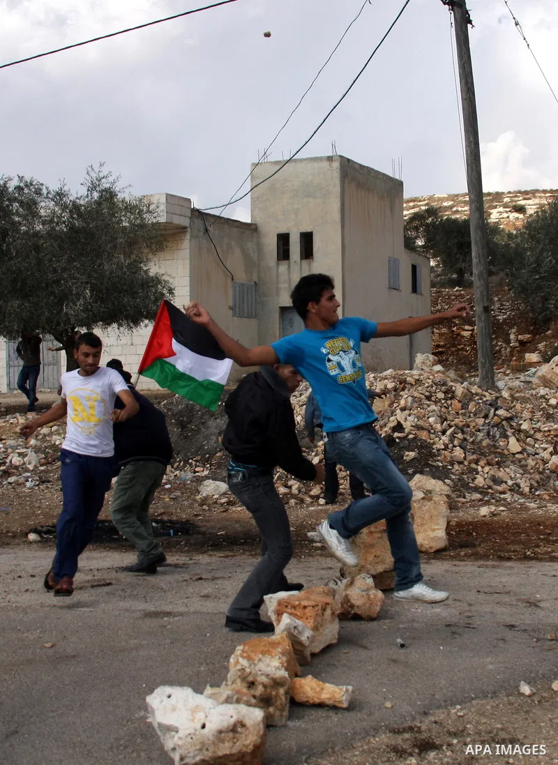 Palestinian youths hurl stones towards Israeli soldiers during clashes following a protest against the closure of a road during the second Intifada (began late September 2000) by Jewish settlers from the nearby settlemen...