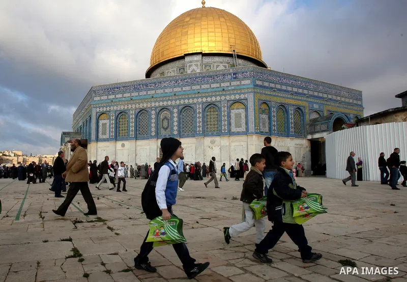 Palestinians walk in front of the Dome of the Rock on the compound known to Muslims as al-Haram al-Sharif, and to Jews as Temple Mount, in Jerusalem's Old city, on the first day of Eid al-Adha November 6, 2011. Muslims a...