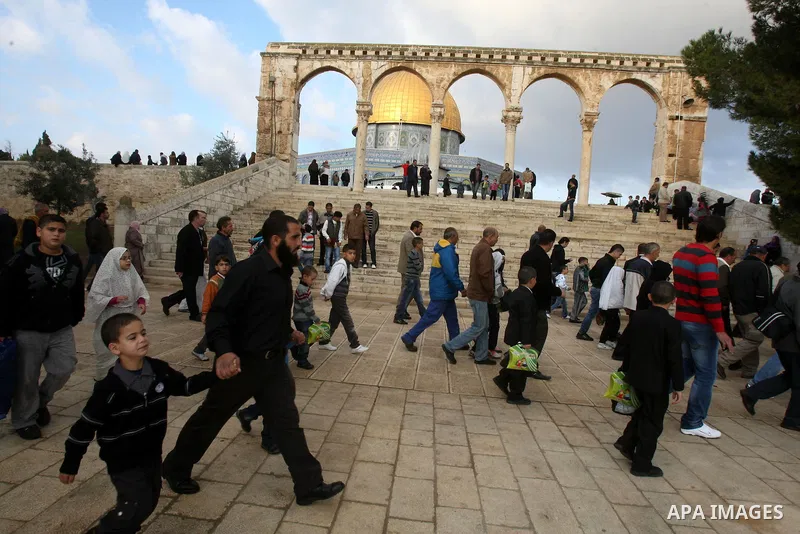Palestinians walk in front of the Dome of the Rock on the compound known to Muslims as al-Haram al-Sharif, and to Jews as Temple Mount, in Jerusalem's Old city, on the first day of Eid al-Adha November 6, 2011. Muslims a...
