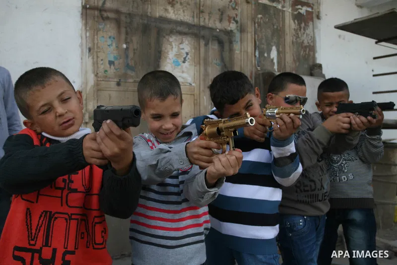 A Palestinians boys play with a toy gun in the West Bank city of Ramallah Nov.06, 2011. Muslims worldwide celebrate Eid al-Adha, or the Feast of the Sacrifice, by sacrificial killings of livestock to commemorate a religi...