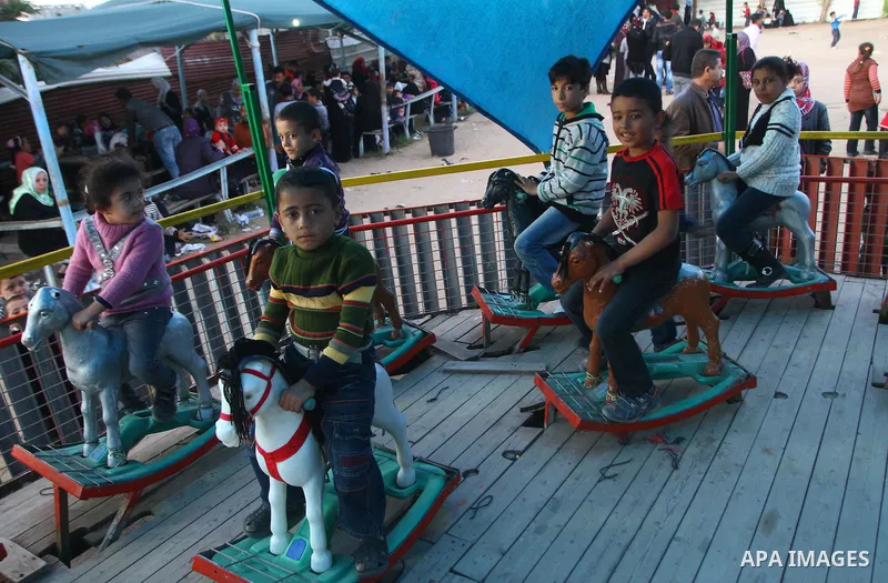 Palestinians enjoy a ride in an amusement park, during Eid al-Adha in Gaza City, Nov. 9, 2011. Muslims worldwide celebrate Eid al-Adha, or the Feast of the Sacrifice, with the sacrificial killing of livestock to commemor...