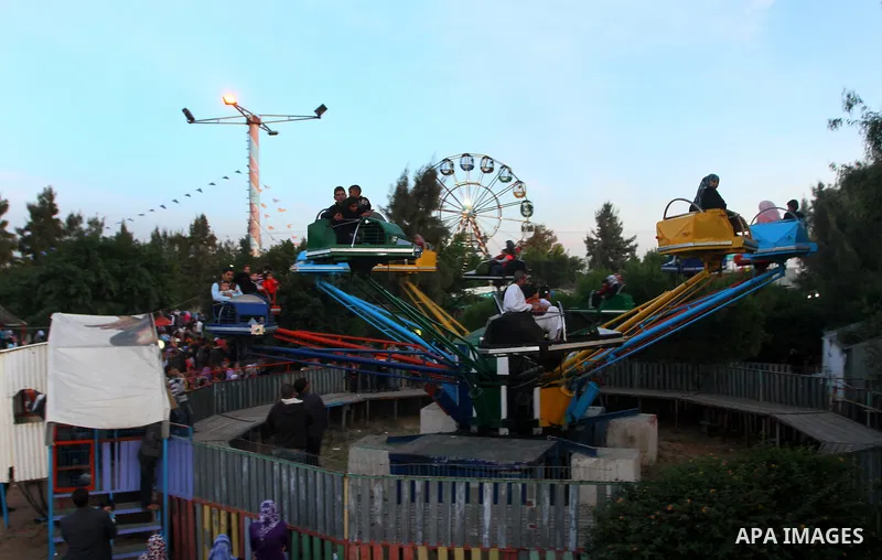 Palestinians enjoy a ride in an amusement park, during Eid al-Adha in Gaza City, Nov. 9, 2011. Muslims worldwide celebrate Eid al-Adha, or the Feast of the Sacrifice, with the sacrificial killing of livestock to commemor...