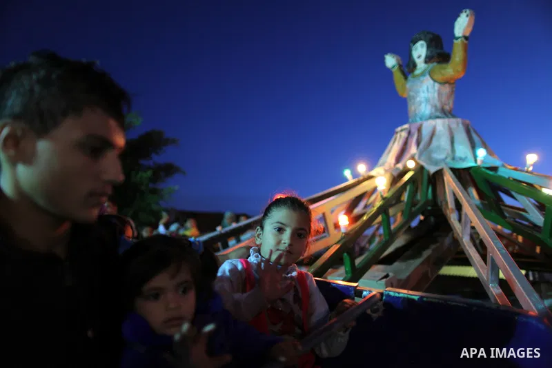 Palestinians enjoy a ride in an amusement park, during Eid al-Adha in Gaza City, Nov. 10, 2011. Muslims worldwide celebrate Eid al-Adha, or the Feast of the Sacrifice, with the sacrificial killing of livestock to commemo...