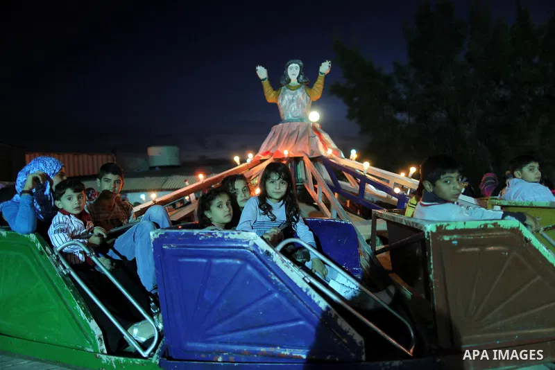 Palestinians enjoy a ride in an amusement park, during Eid al-Adha in Gaza City, Nov. 10, 2011. Muslims worldwide celebrate Eid al-Adha, or the Feast of the Sacrifice, with the sacrificial killing of livestock to commemo...