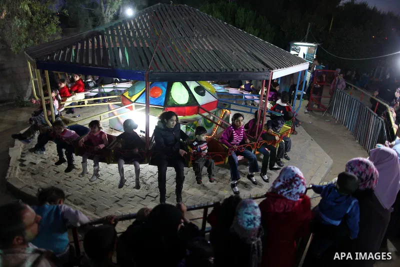 Palestinians enjoy a ride in an amusement park, during Eid al-Adha in Gaza City, Nov. 10, 2011. Muslims worldwide celebrate Eid al-Adha, or the Feast of the Sacrifice, with the sacrificial killing of livestock to commemo...