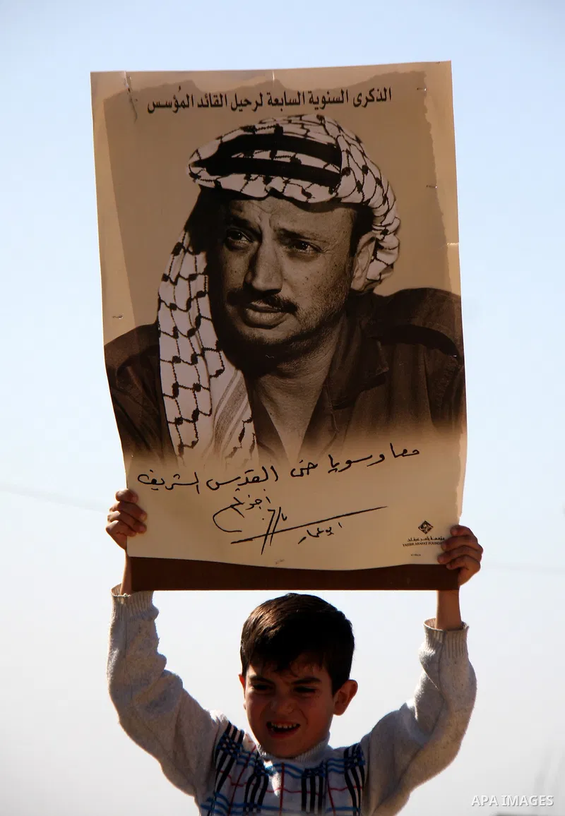 Palestinian protestors hold pictures of late leader Yasser Arafat in front of Israeli forces during a weekly demonstration against Israeli-occupation in the northern West Bank village of Kfar Kadum, on November 11, 2011....