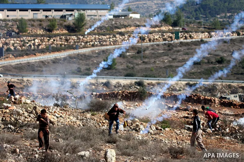 Palestinian protesters try to avoid tear gas shoot by Israeli soldiers during clashes between Israeli security forces and Palestinian demonstrators at a weekly protest in the West Bank village of Nabi Saleh, near Ramalla...
