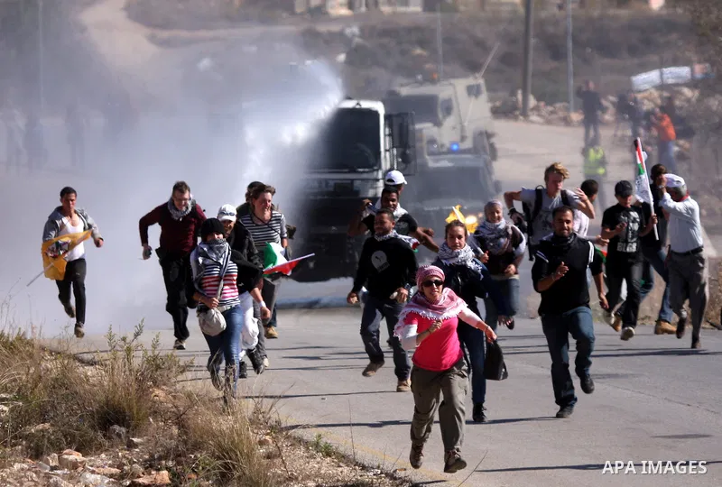 Palestinian protesters try to avoid tear gas shoot by Israeli soldiers during clashes between Israeli security forces and Palestinian demonstrators at a weekly protest in the West Bank village of Nabi Saleh, near Ramalla...