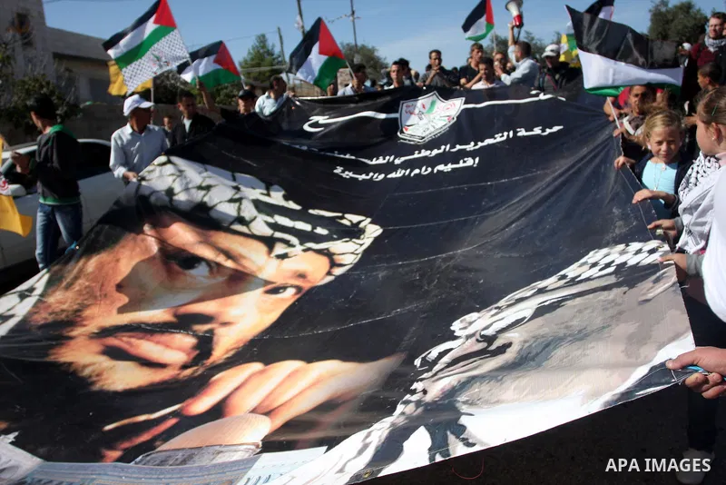 Palestinian protesters hold a banner with the picture of the late Palestinian chairman Yasser Arafat during clashes between Israeli security forces and Palestinian demonstrators at a weekly protest in the West Bank villa...