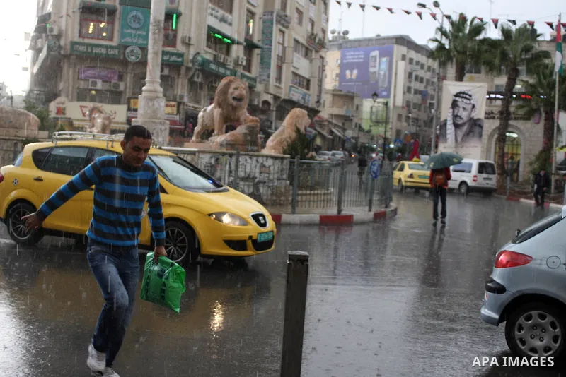 Palestinians walk in a street during heavy rains in the West Bank city of Ramallah on Nov. 14,2011. Photo by Issam Rimawi