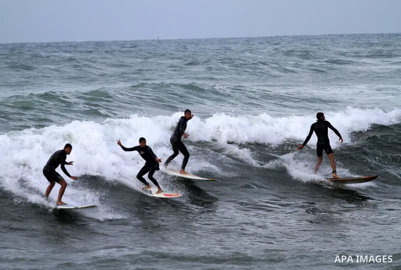 Palestinian youths surf in the Mediterranean Sea off the coast of Gaza City, as a cold and windy weather hits Gaza Strip, on Nov. 16,2011. Photo by Mohammed Asad