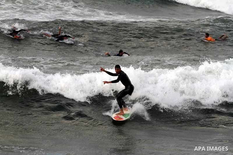 Palestinian youths surf in the Mediterranean Sea off the coast of Gaza City, as a cold and windy weather hits Gaza Strip, on Nov. 16,2011. Photo by Mohammed Asad