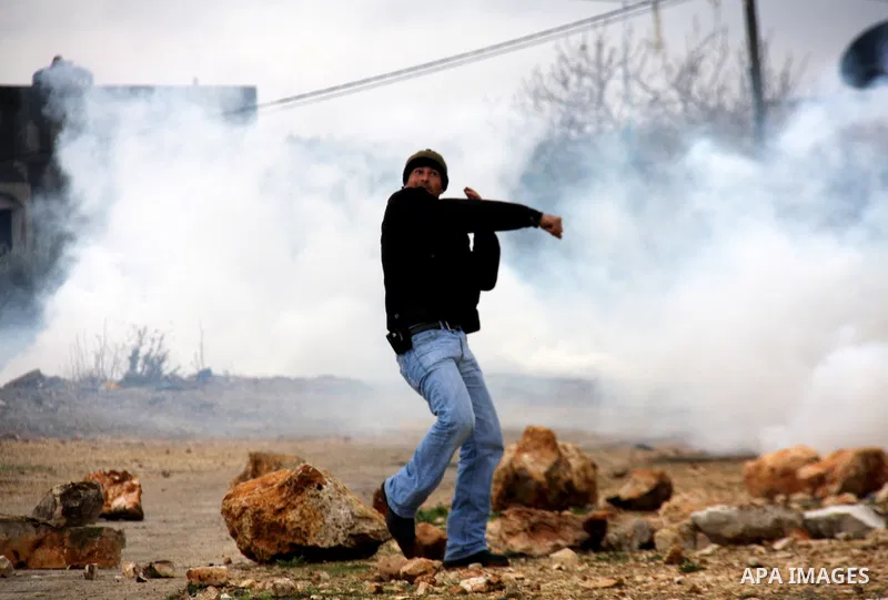 A Palestinian demonstrator throws a stone at at Israeli security forces , who are seeking access to their land near Kufr Qaddum, near the northern West Bank Jewish settlement of Kdumim, Friday, Nov. 18, 2011. Photo by Wa...