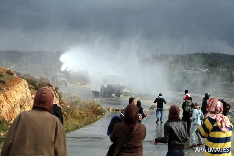 Palestinian youths and Israeli troops clash following a weekly demonstration against Israeli settlement expansion (background), in the West Bank village of Nabi Saleh, on November 18, 2011. Photo by Issam Rimawi