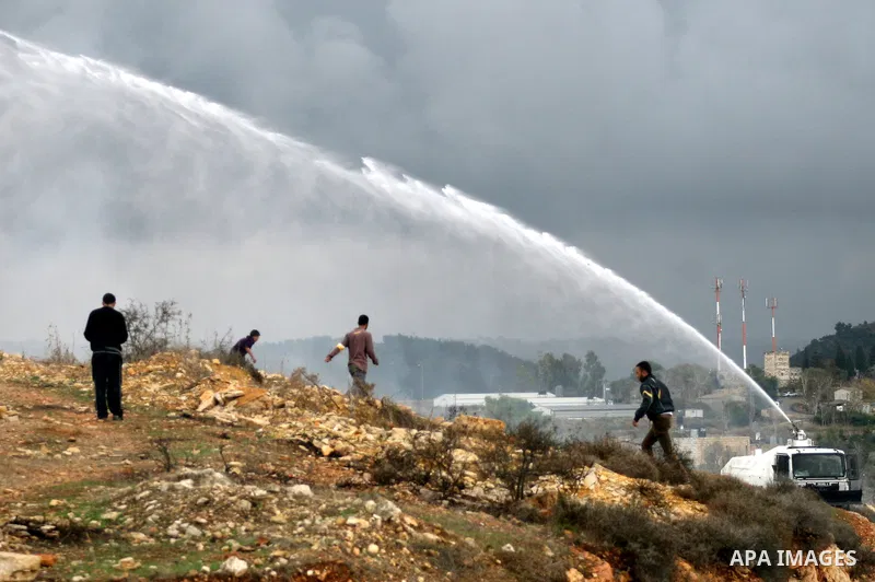 Palestinian youths and Israeli troops clash following a weekly demonstration against Israeli settlement expansion (background), in the West Bank village of Nabi Saleh, on November 18, 2011. Photo by Issam Rimawi
