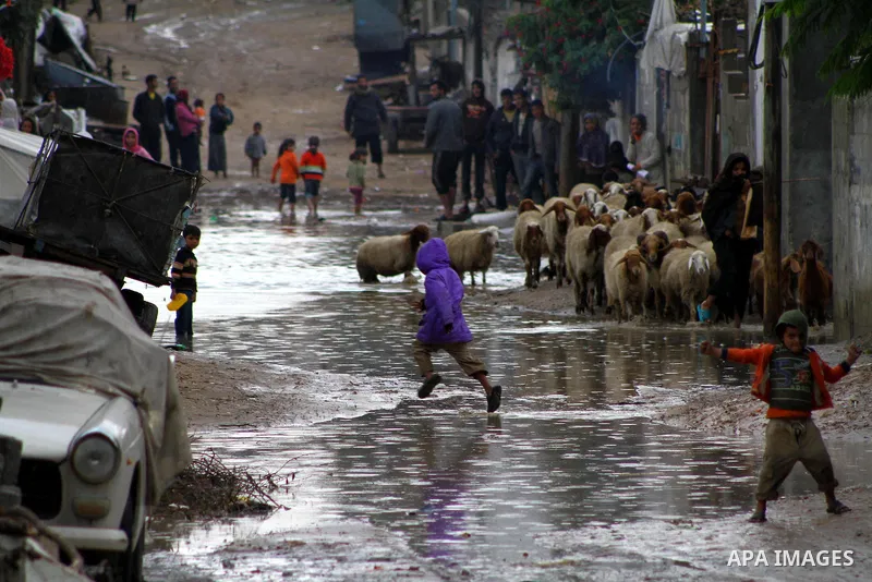 Palestinian boys play at a pool of rain water in refugee camp in Gaza Strip, On Nov. 19, 2011. Photo by Ashraf Amra