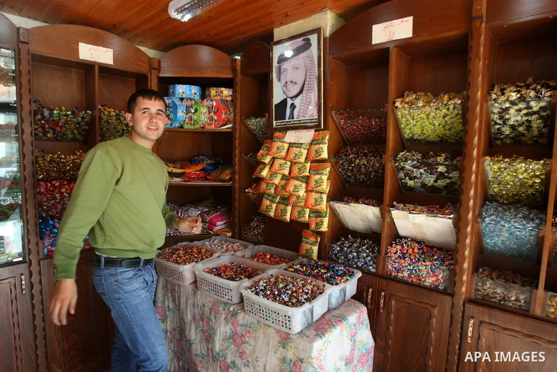 A Palestinian holds up photographs of King Abdullah in shop in the West Bank city of Nablus, Nov. 21, 201. Photo by Wagdi Eshtayah