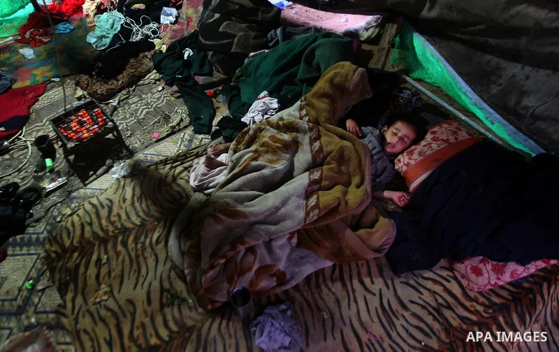 Palestinian bedouins sit inside their tent during heavy rain and cold winds in a camp for poor people in Al-Nussirat refugee camp, central Gaza Strip on 21 November 2011. Photo by Ali Jadallah
