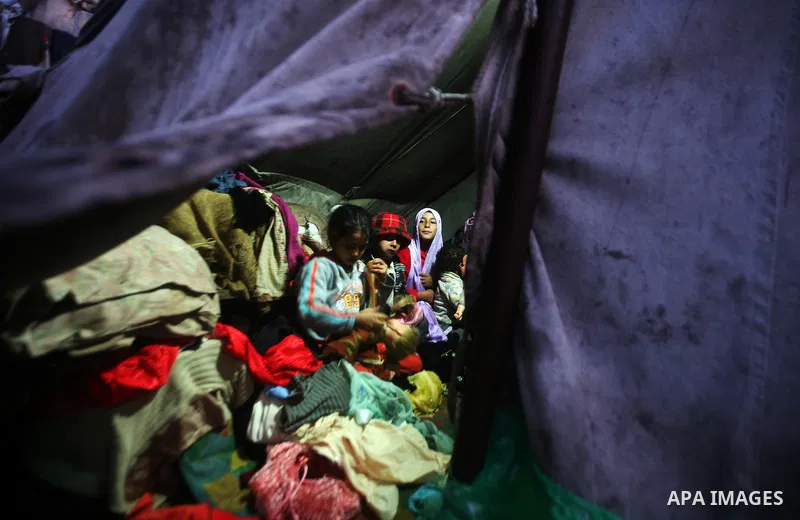 Palestinian bedouins sit inside their tent during heavy rain and cold winds in a camp for poor people in Al-Nussirat refugee camp, central Gaza Strip on 21 November 2011. Photo by Ali Jadallah