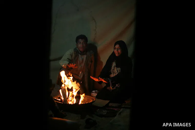 Palestinian bedouins sit inside their tent during heavy rain and cold winds in a camp for poor people in Al-Nussirat refugee camp, central Gaza Strip on 21 November 2011. Photo by Ali Jadallah
