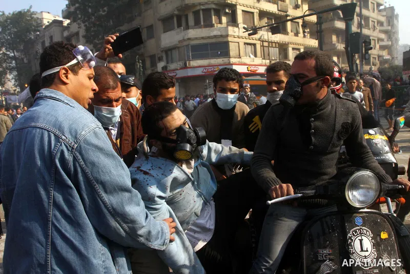Protesters help another protester injured during clashes with riot police near Tahrir square in Cairo, Egypt, Wednesday, Nov. 23, 2011. Egyptian police are clashing with anti-government protesters for a fifth day in Cair...