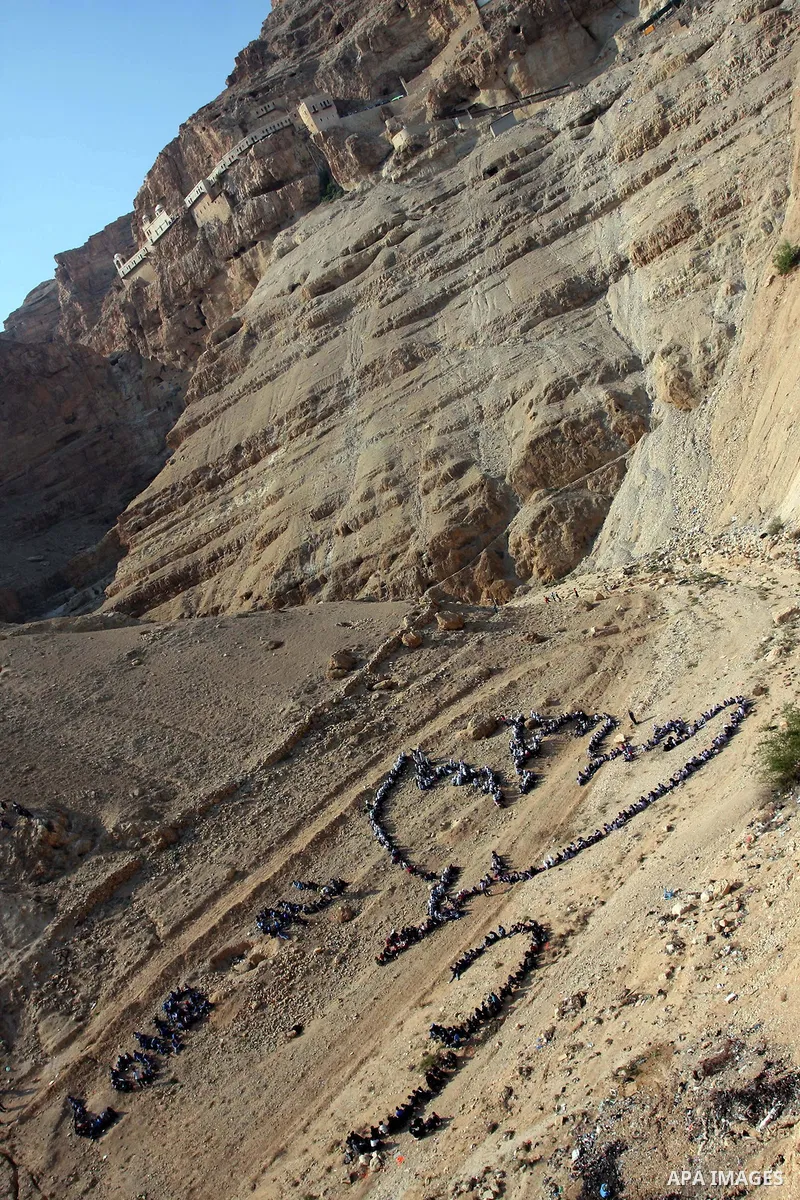 Palestinian children stand to form Pablo Picasso's Dove of Peace as part of a project by British aerial artist John Quigley and the United Nations Relief Works Agency (UNRWA), at the foot of the Mount of Temptation in th...