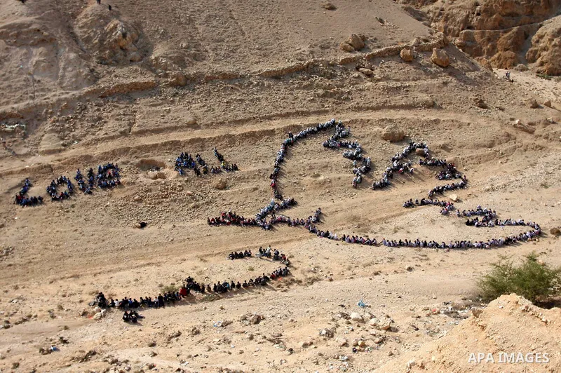 Palestinian children stand to form Pablo Picasso's Dove of Peace as part of a project by British aerial artist John Quigley and the United Nations Relief Works Agency (UNRWA), at the foot of the Mount of Temptation in th...