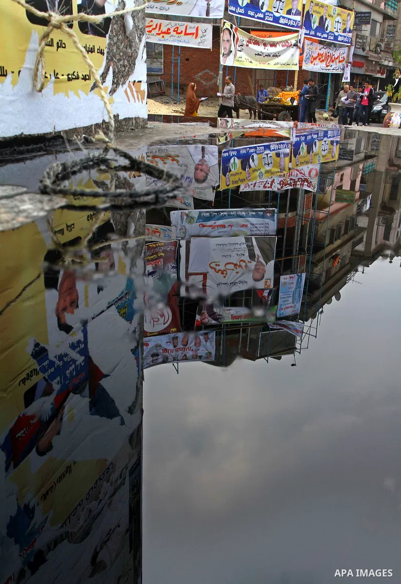 Egyptians walk past electoral campaign banners in Cairo on November 26, 2011 ahead of a three-round parliamentary election. The parliamentary elections that get underway on November 28 will be the first polls since a pop...