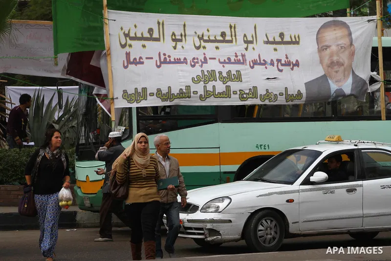 Egyptians walk past electoral campaign banners in Cairo on November 26, 2011 ahead of a three-round parliamentary election. The parliamentary elections that get underway on November 28 will be the first polls since a pop...