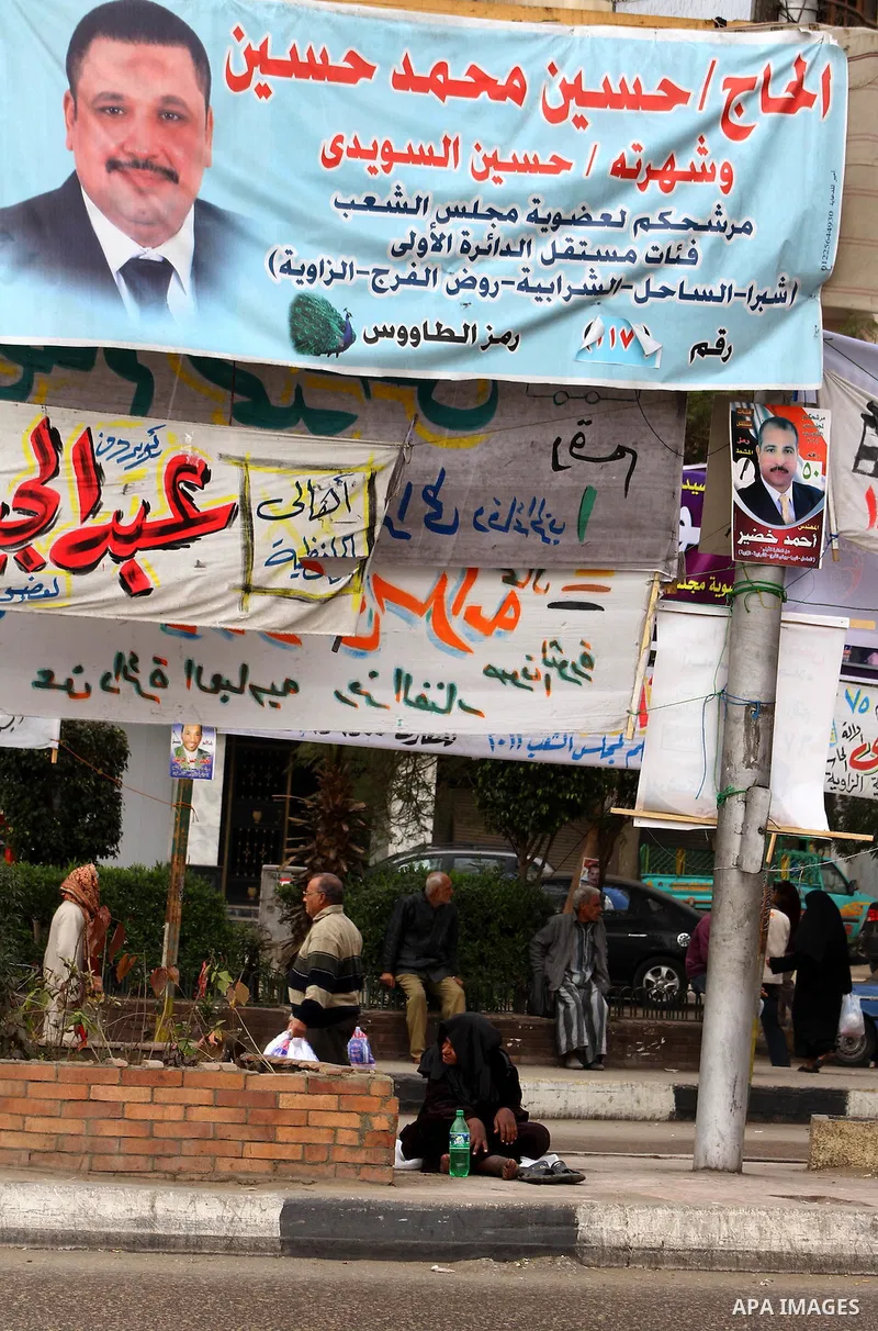 Egyptians walk past electoral campaign banners in Cairo on November 26, 2011 ahead of a three-round parliamentary election. The parliamentary elections that get underway on November 28 will be the first polls since a pop...