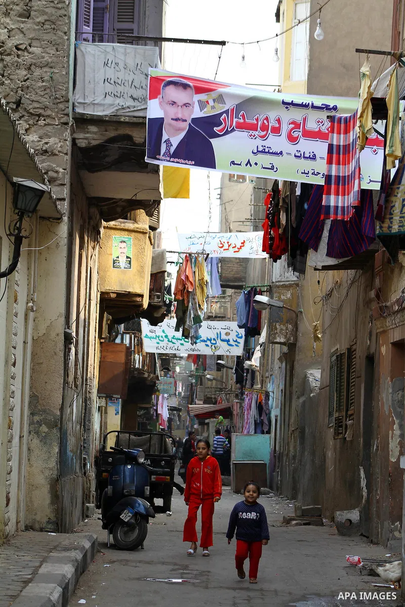 Egyptians walk past electoral campaign banners in Cairo on November 26, 2011 ahead of a three-round parliamentary election. The parliamentary elections that get underway on November 28 will be the first polls since a pop...
