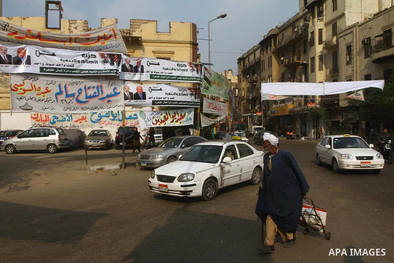Egyptians walk past electoral campaign banners in Cairo on November 26, 2011 ahead of a three-round parliamentary election. The parliamentary elections that get underway on November 28 will be the first polls since a pop...
