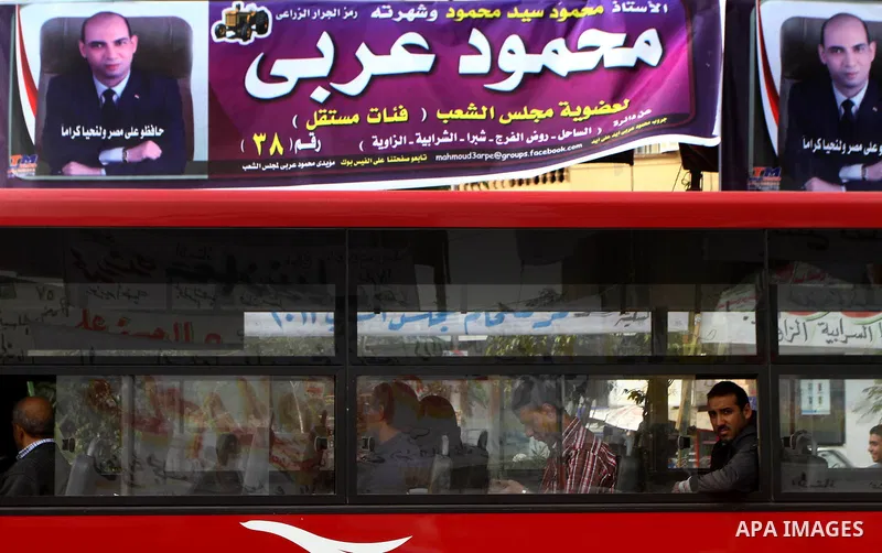 Egyptians walk past electoral campaign banners in Cairo on November 26, 2011 ahead of a three-round parliamentary election. The parliamentary elections that get underway on November 28 will be the first polls since a pop...