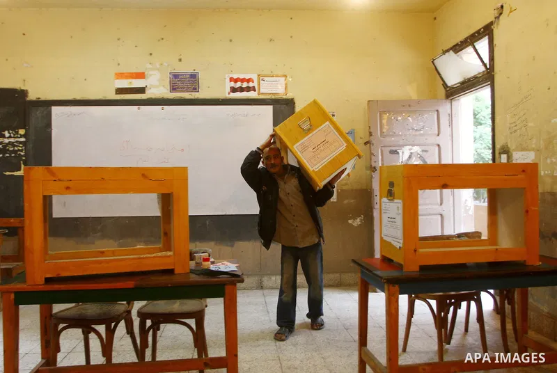 An Egyptian man carries an electoral box into a polling station at a school in Cairo on November 27, 2011 on the eve of the first parliament elections since the end of the 30-year rule of strongman Hosni Mubarak. Photo b...
