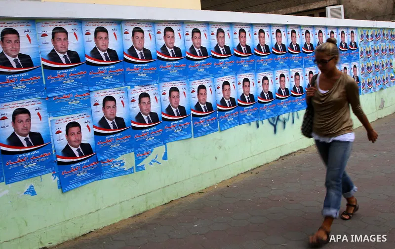 A foreign woman walks past electoral campaign posters and banners for candidates in Cairo on November 27, 2011 on the eve of the first parliament elections since the end of the 30-year rule of strongman Hosni Mubarak. Ph...