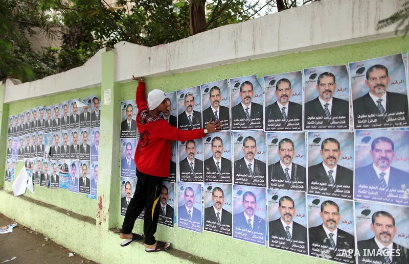 An Egyptian walks past electoral campaign posters and banners for candidates in Cairo on November 27, 2011 on the eve of the first parliament elections since the end of the 30-year rule of strongman Hosni Mubarak. Photo...