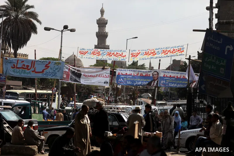 Egyptians walk beneath elections campaign banners and posters in Cairo on November 27, 2011 on the eve of the first parliament elections since the end of the 30-year rule of strongman Hosni Mubarak. Photo by Wissam Nassa...