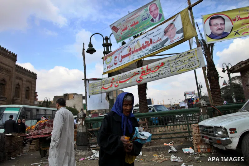Egyptians walk beneath elections campaign banners and posters in Cairo on November 27, 2011 on the eve of the first parliament elections since the end of the 30-year rule of strongman Hosni Mubarak. Photo by Wissam Nassa...
