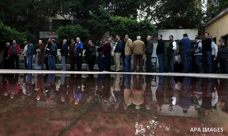 Voters line up inside a polling center beneath campaign posters on the first day of parliamentary elections in Cairo, Egypt, Monday, Nov. 28, 2011. Shaking off years of political apathy, Egyptians on Monday began voting...