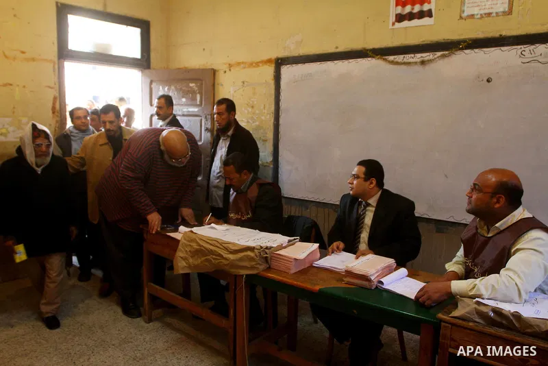 Elections staff members hel voters to determine their number during the vote in the first round of Egypt's parliamentary elections at a polling station in Cairo during the first round of Egypt's Parliamentary elections a...