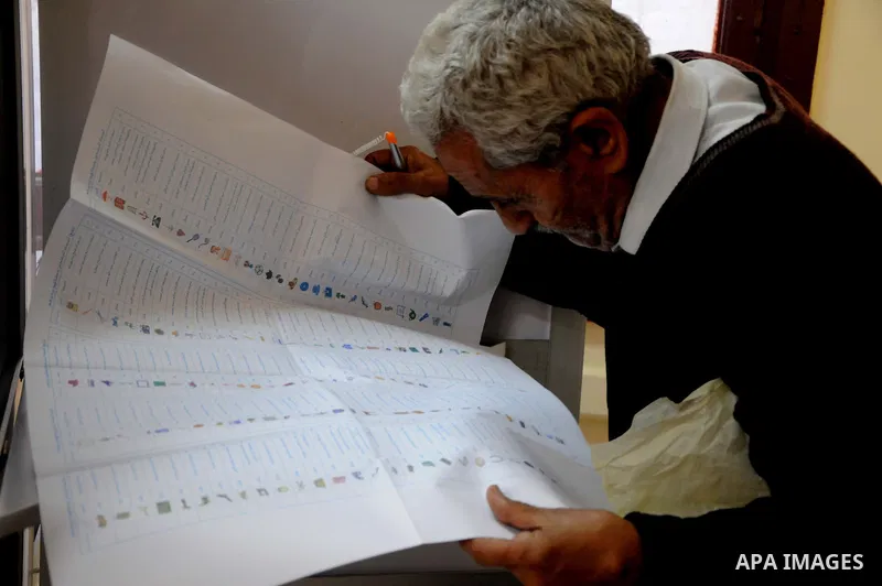 Egyptian man read voting materials at a polling center in Cairo, Egypt, Monday, Nov. 28, 2011.Voting began on Monday in Egypt's first parliamentary elections since longtime authoritarian leader Hosni Mubarak was ousted i...